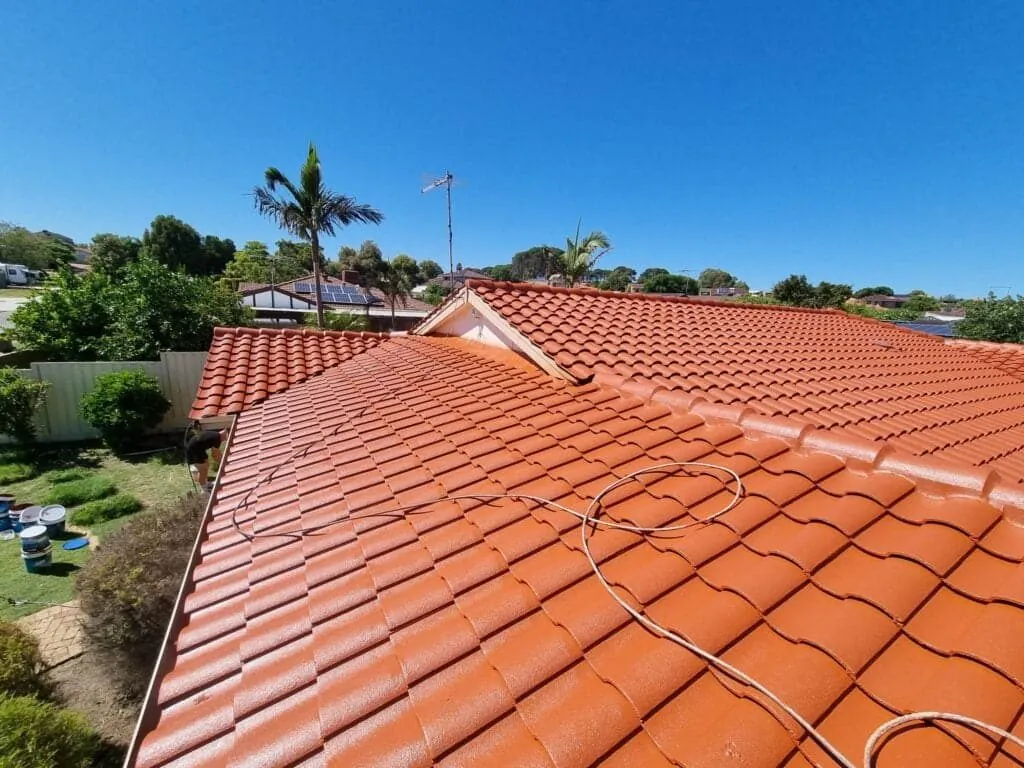Freshly coated terracotta tile roof on a Perth home with the wash down hose still lying across the tiles