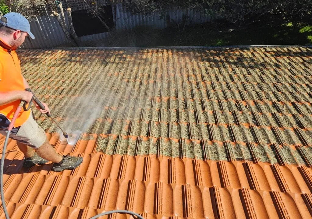 Kili & Cousins tradesman pressure cleaning moss and lichen off a tile roof